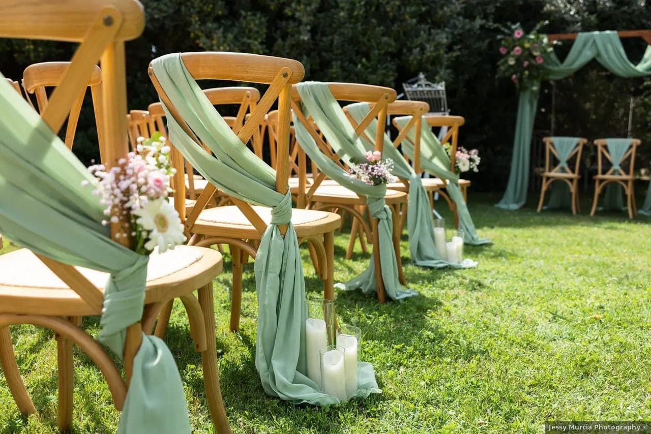 Cérémonie laïque sous les arbres avec chaises en bois et voilages