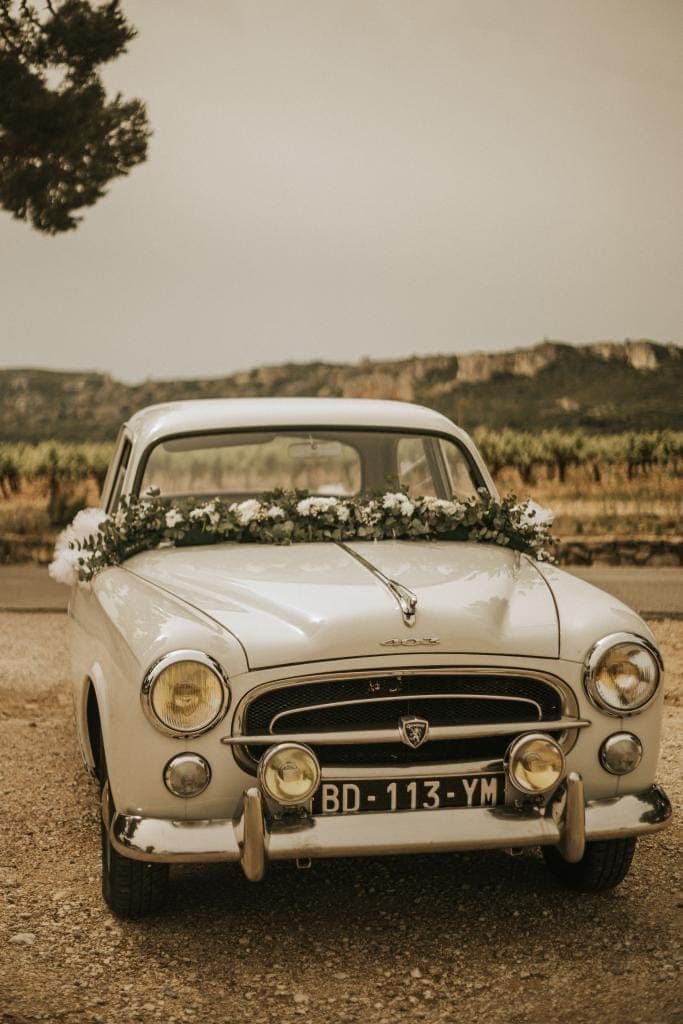 Séance photo des mariés dans les vignes en Provence avec voiture ancienne